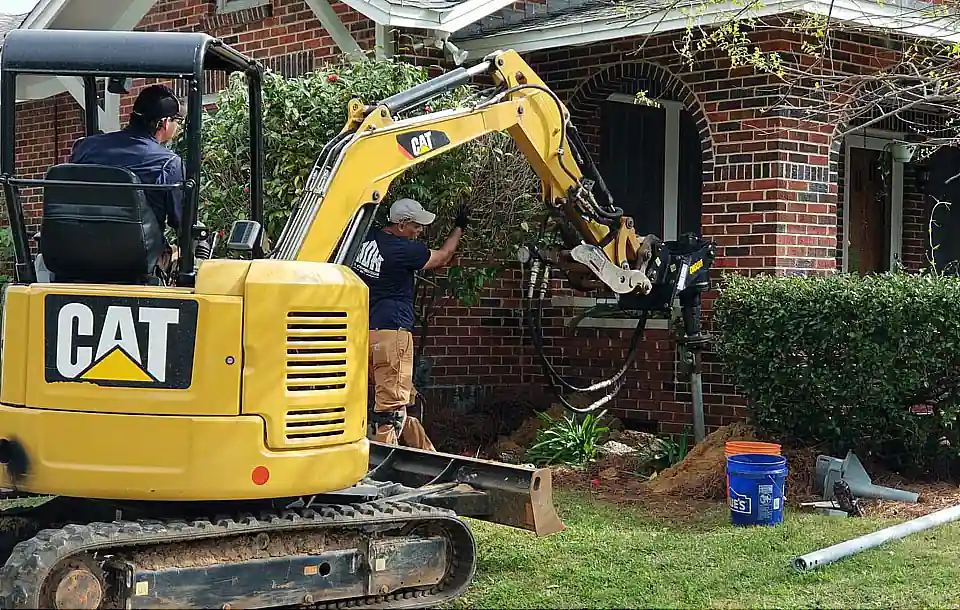 MDH Foundation Repair technician using a mini excavator to install helical piers in a gulf coast home